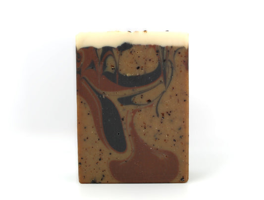 Brown bar soap with coffee grounds and swirls on a white background.