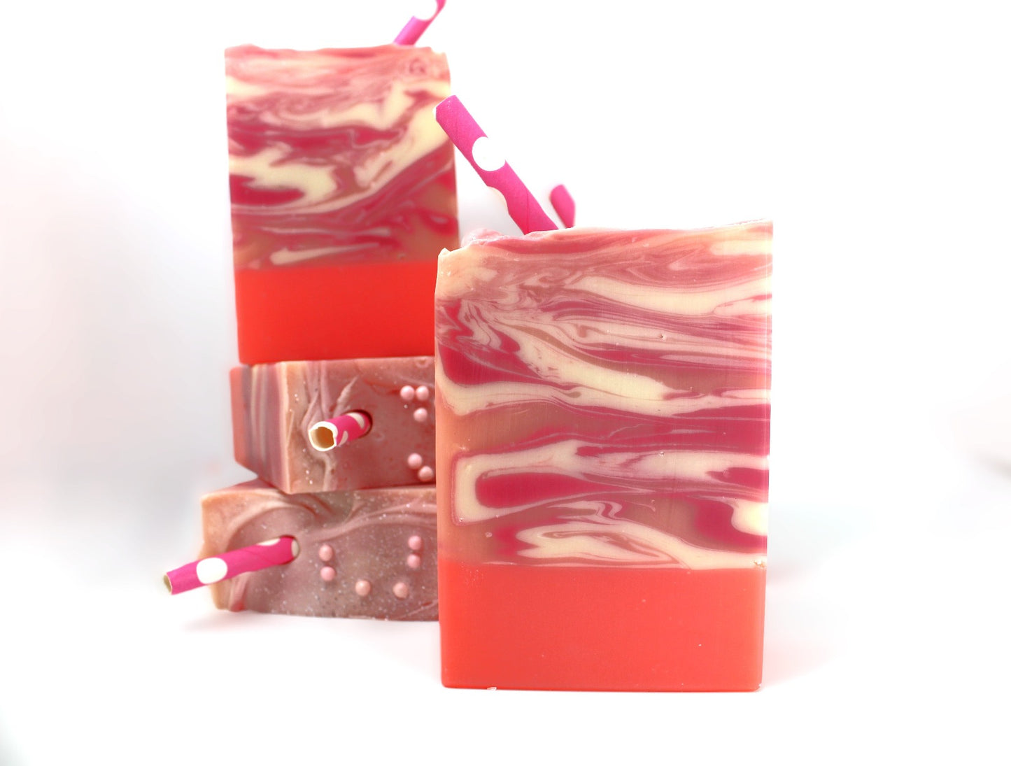 4 bars of Pink, White, and Orange bar soap with swirls and a pink paper straw on a white background.