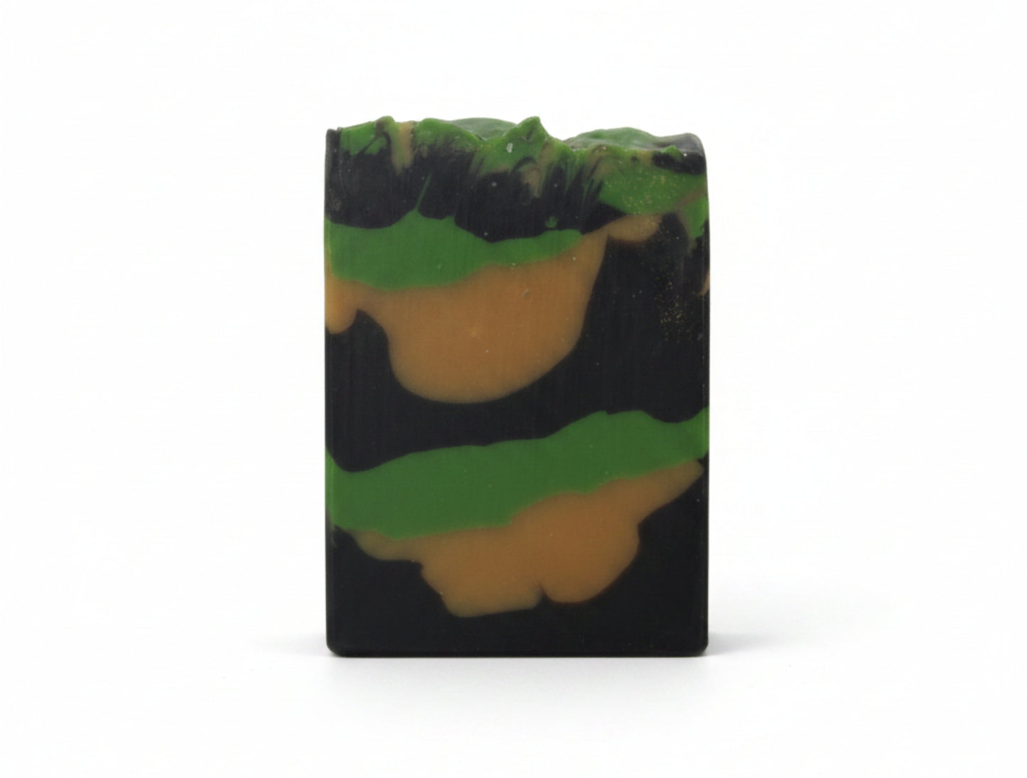 Handmade black bar of soap with green and yellow layers on a white background
