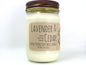White wax candle in a mason jar with a rustic brown metal lid. Kraft brown label with black text. White background.
