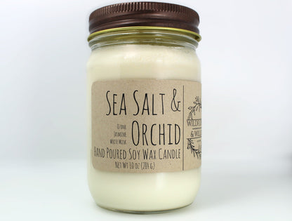 White wax candle in a mason jar with a rustic brown metal lid. Kraft brown label with black text. White background.