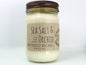 White wax candle in a mason jar with a rustic brown metal lid. Kraft brown label with black text. White background.