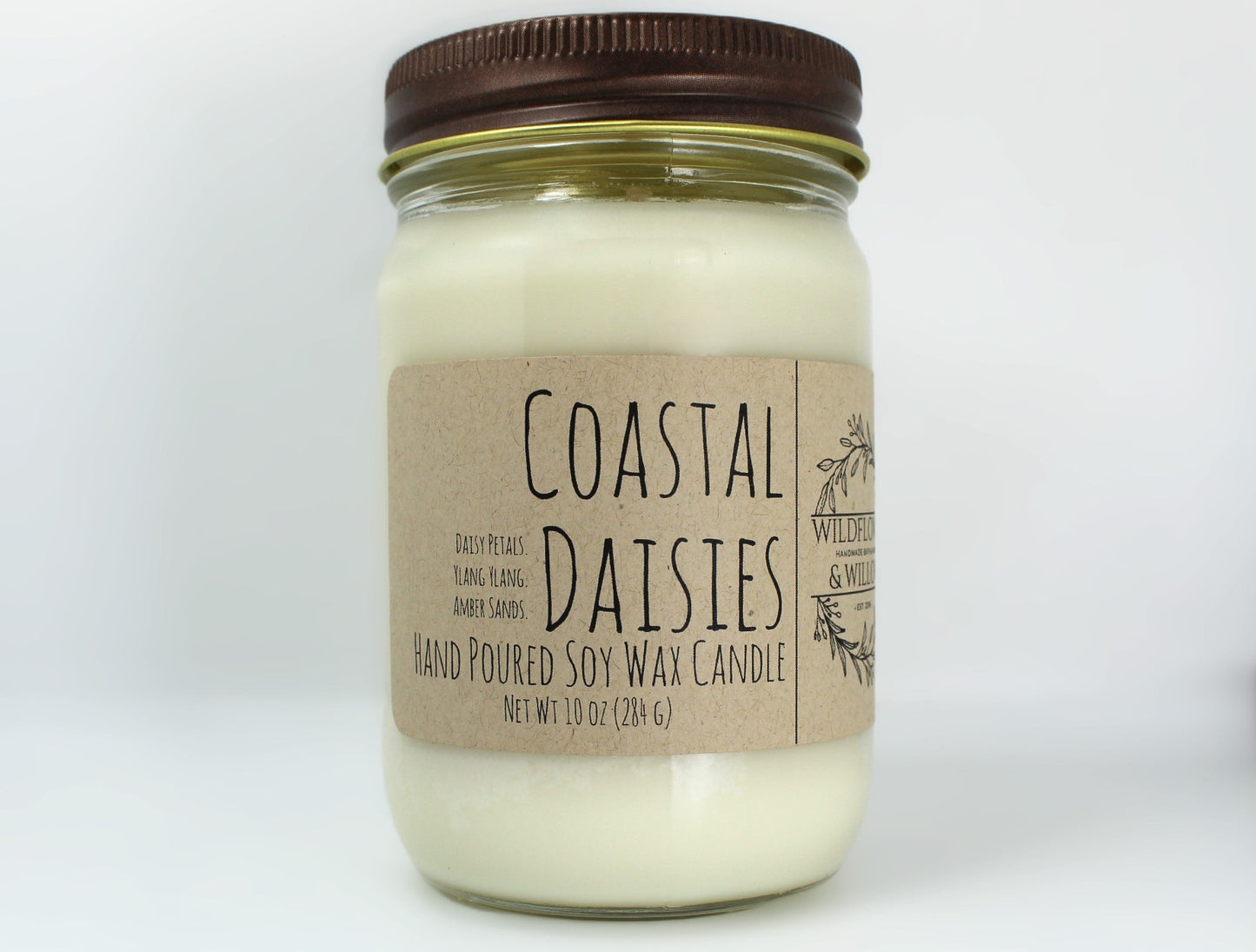 White wax candle in a mason jar with a rustic brown metal lid. Kraft brown label with black text. White background.