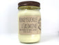 White wax candle in a mason jar with a rustic brown metal lid. Kraft brown label with black text. White background.
