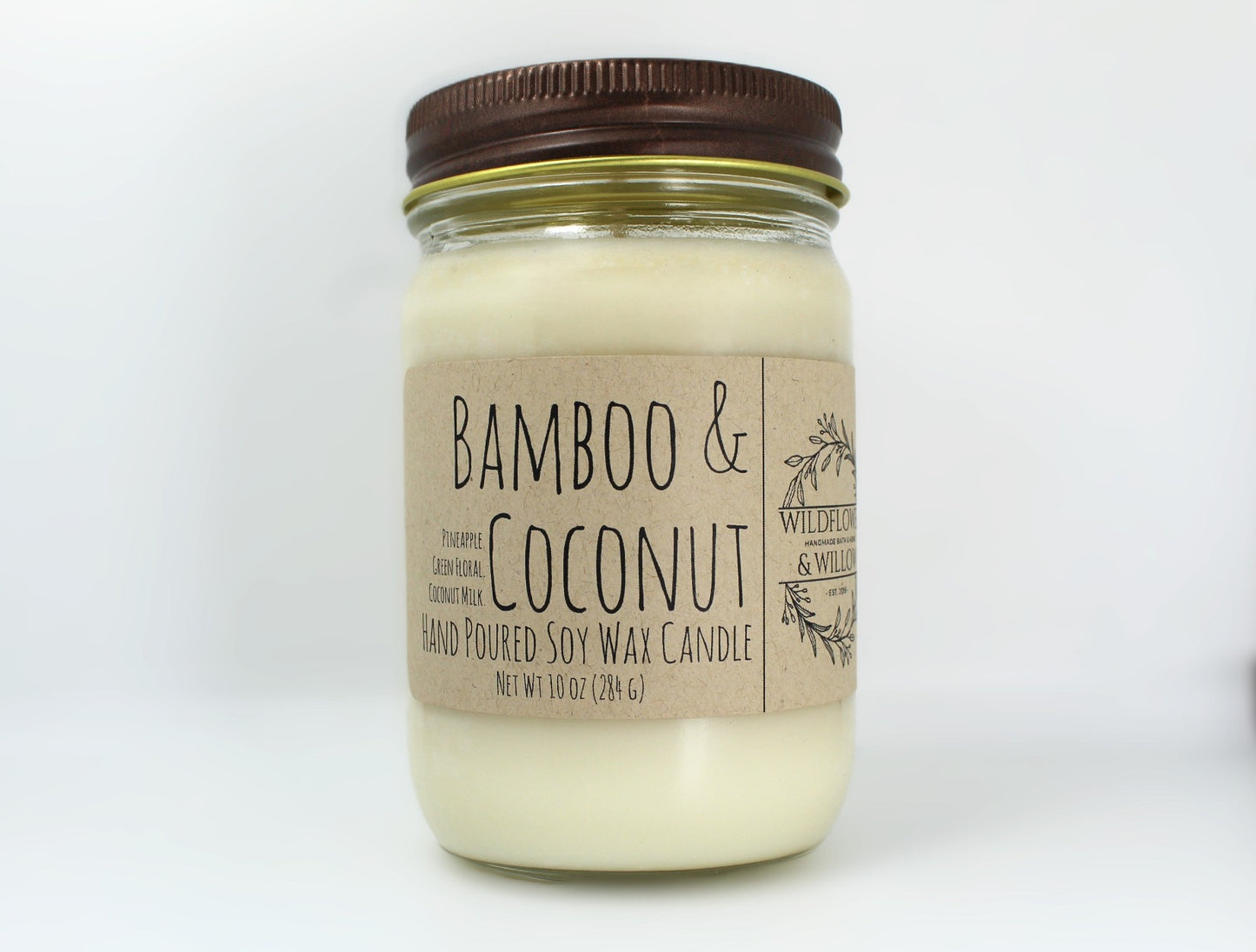 White wax candle in a mason jar with a rustic brown metal lid. Kraft brown label with black text. White background.