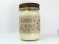 White wax candle in a mason jar with a rustic brown metal lid. Kraft brown label with black text. White background.
