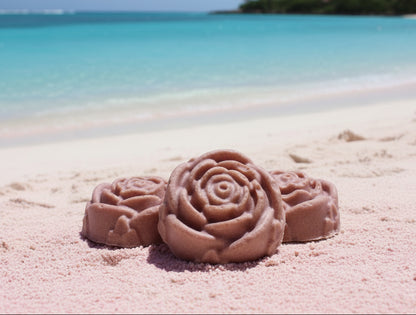 Three rose-shaped mauve soap bars on a pink sand beach