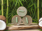3 bars of brown soap surrounded by coconuts and bamboo stalks