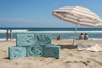 Five blue bars of salt soap with swirls on top on a beachy background