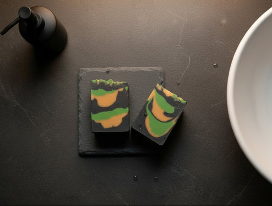 Two handmade bars of soap in a bathroom near a sinnk on a slate soap dish