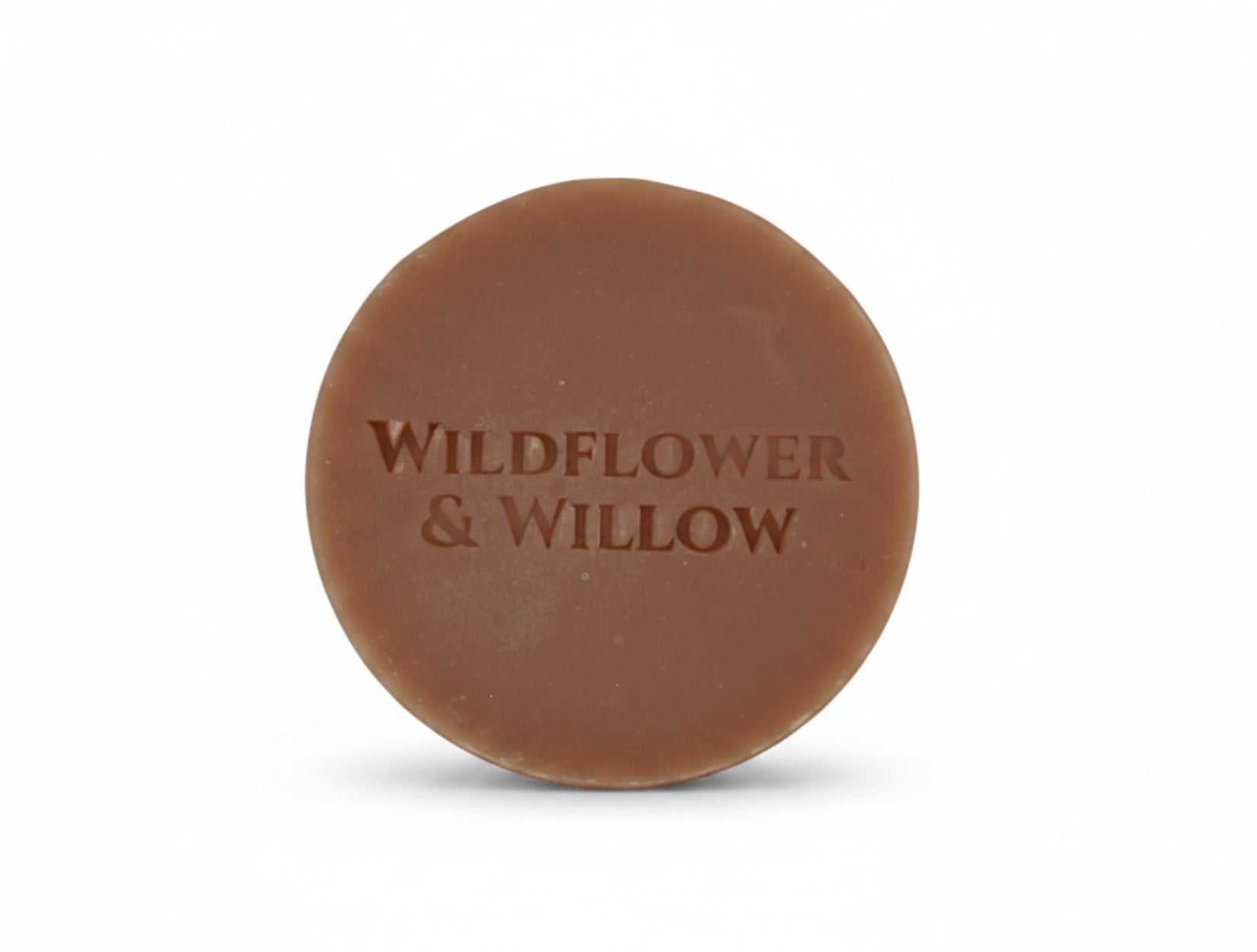 A round pink bar of soap embossed with the brand name 'WILDFLOWER & WILLOW', set against a plain white background.