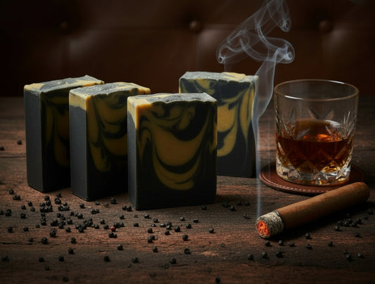 Four rectangular bars of soap on a dark wood surface with gunpowder pellets, a glass of liquor, and a smoking cigar surrounding the soap. 