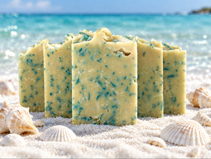 Five cream and blue bars of soap on a beach with seashells