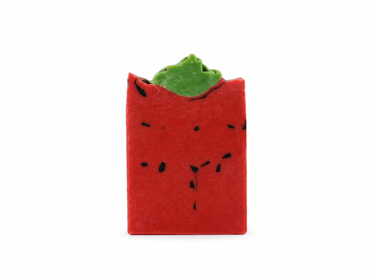 A rectangular bar of red soap with a green top and black specks on a white background